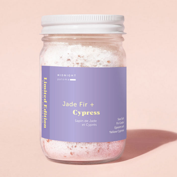 Jar of bath salts with a purple label on a pink background