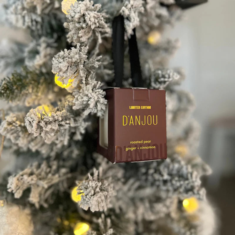 D'ANJOU roasted pear candle packaging hanging on a decorated Christmas tree.