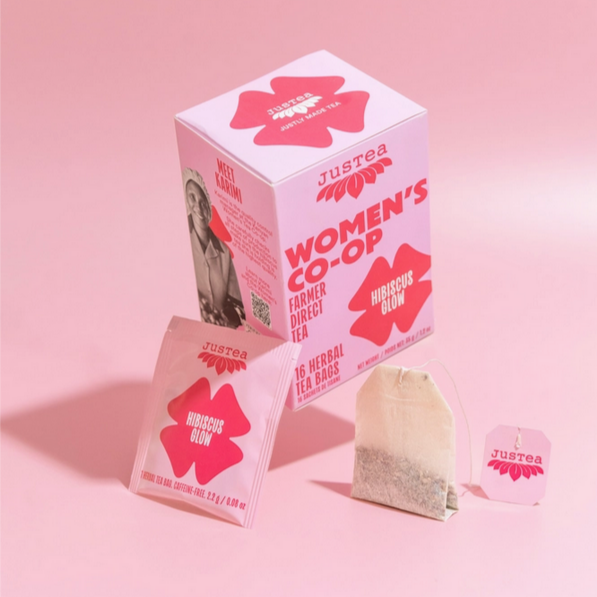 Justea Women's Co-op Hirsutus Glow tea packaging on a pink background