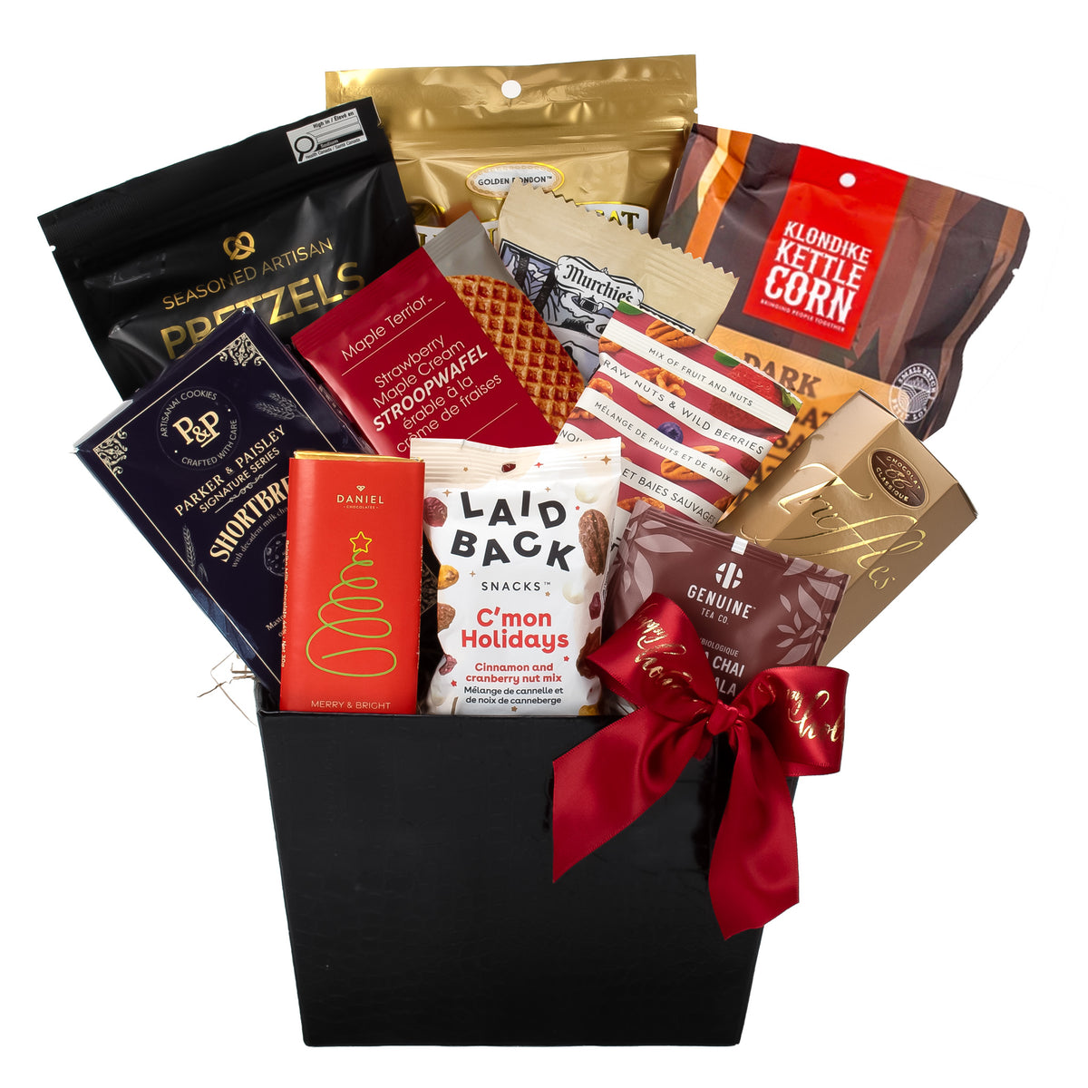 A gourmet gift basket featuring an assortment of packaged snacks, chocolates, and treats arranged in a black rectangular basket with a red ribbon. Visible brands include Pretzels, Klondike Kettle Corn, Maple Cookie, Laid Back Cinnamon Nuts, and Genuine Tea.