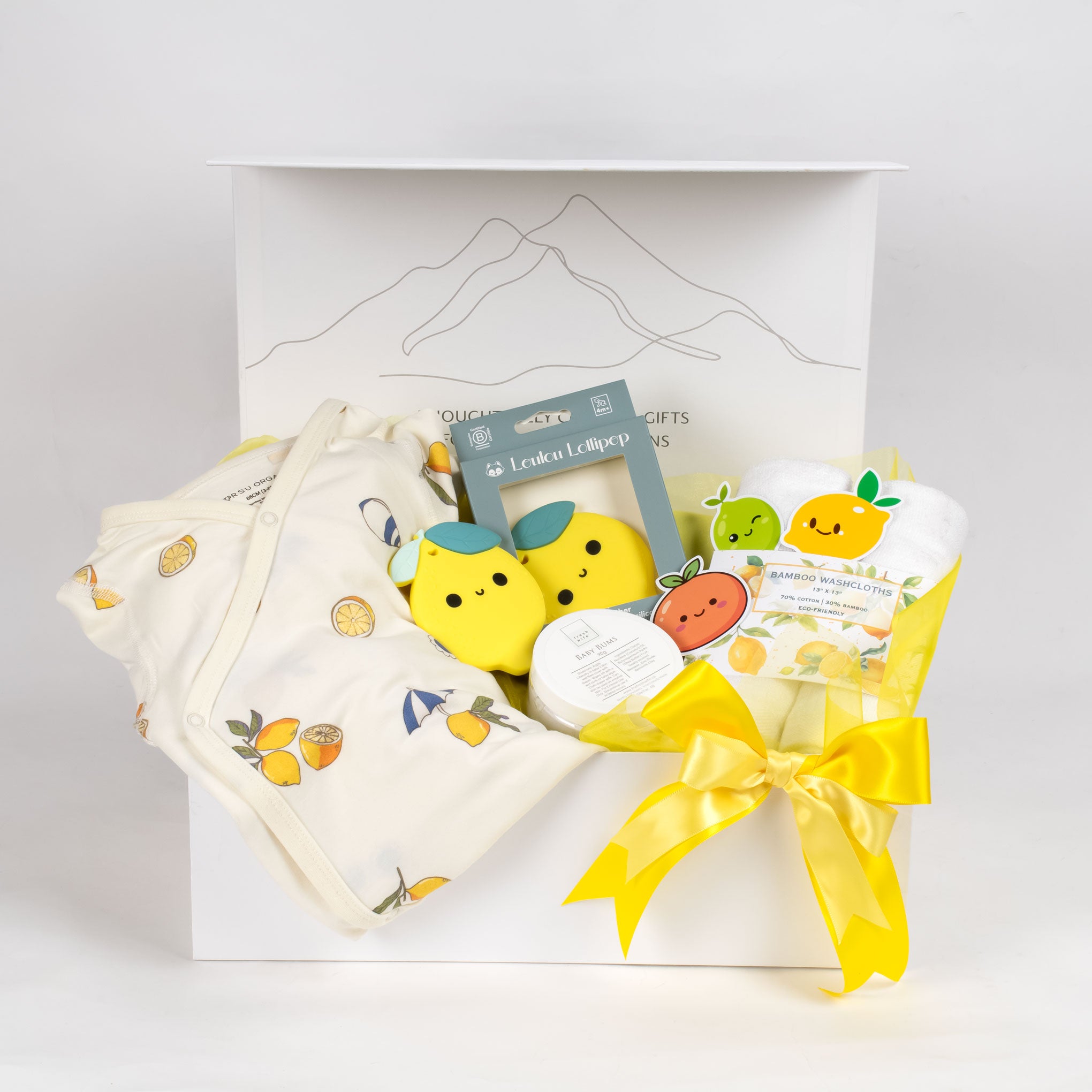 The Main Squeeze unisex baby gift basket featuring vibrant lemon-print clothing, a yellow citrus teether, and themed washcloths. A premium baby shower gift for Vancouver delivery.