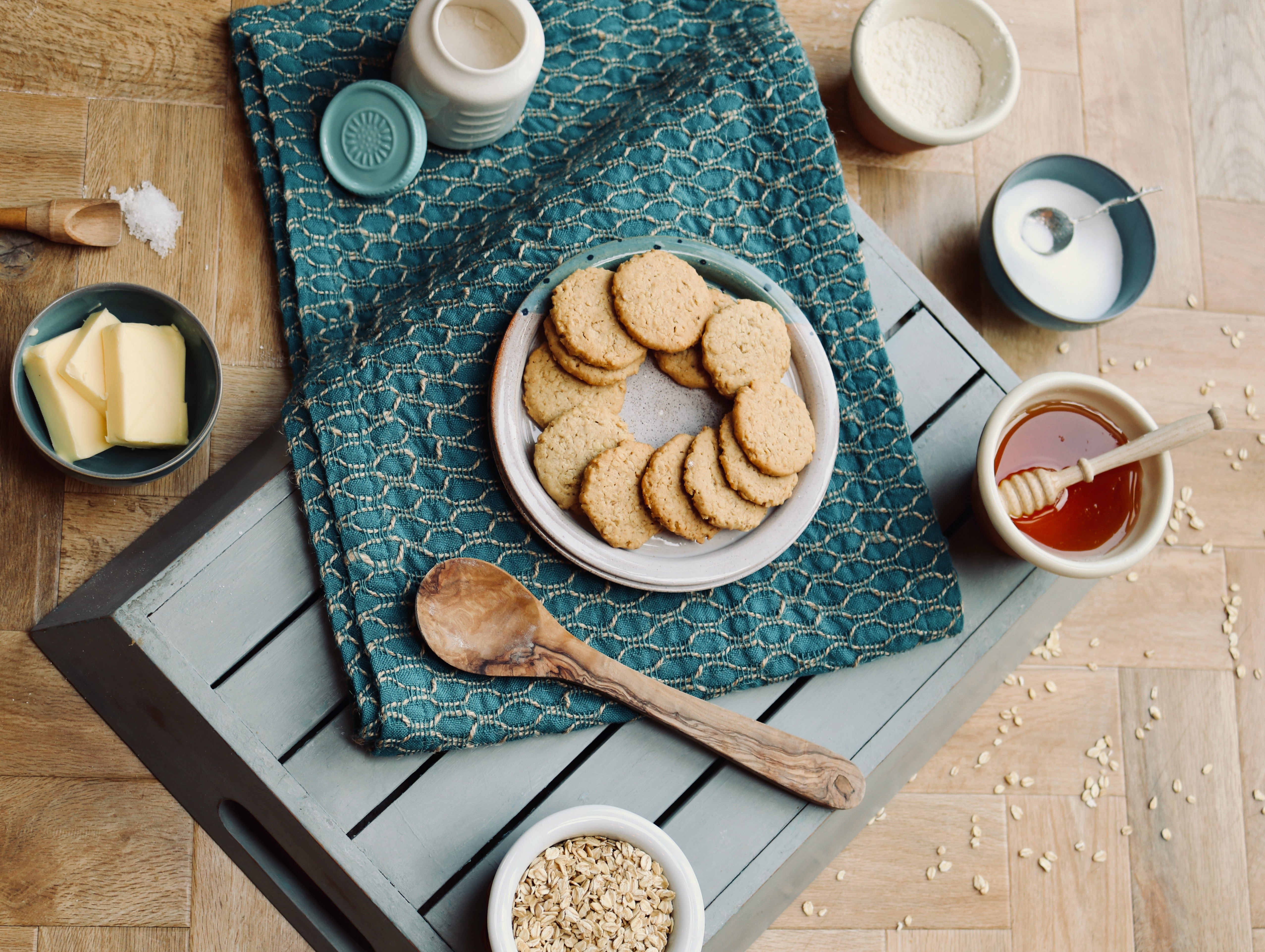 Plate of cookies on a wooden table with honey, butter, and a wooden spoon.