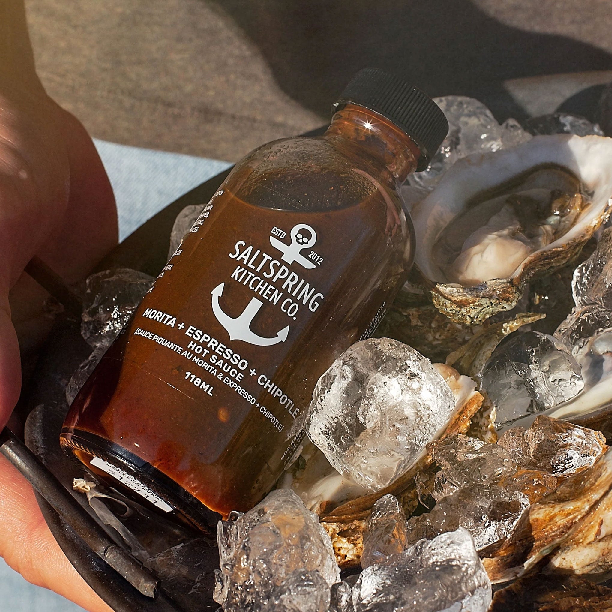 Bottle of Salt Spring Kitchen Co. hot sauce on ice with oysters
