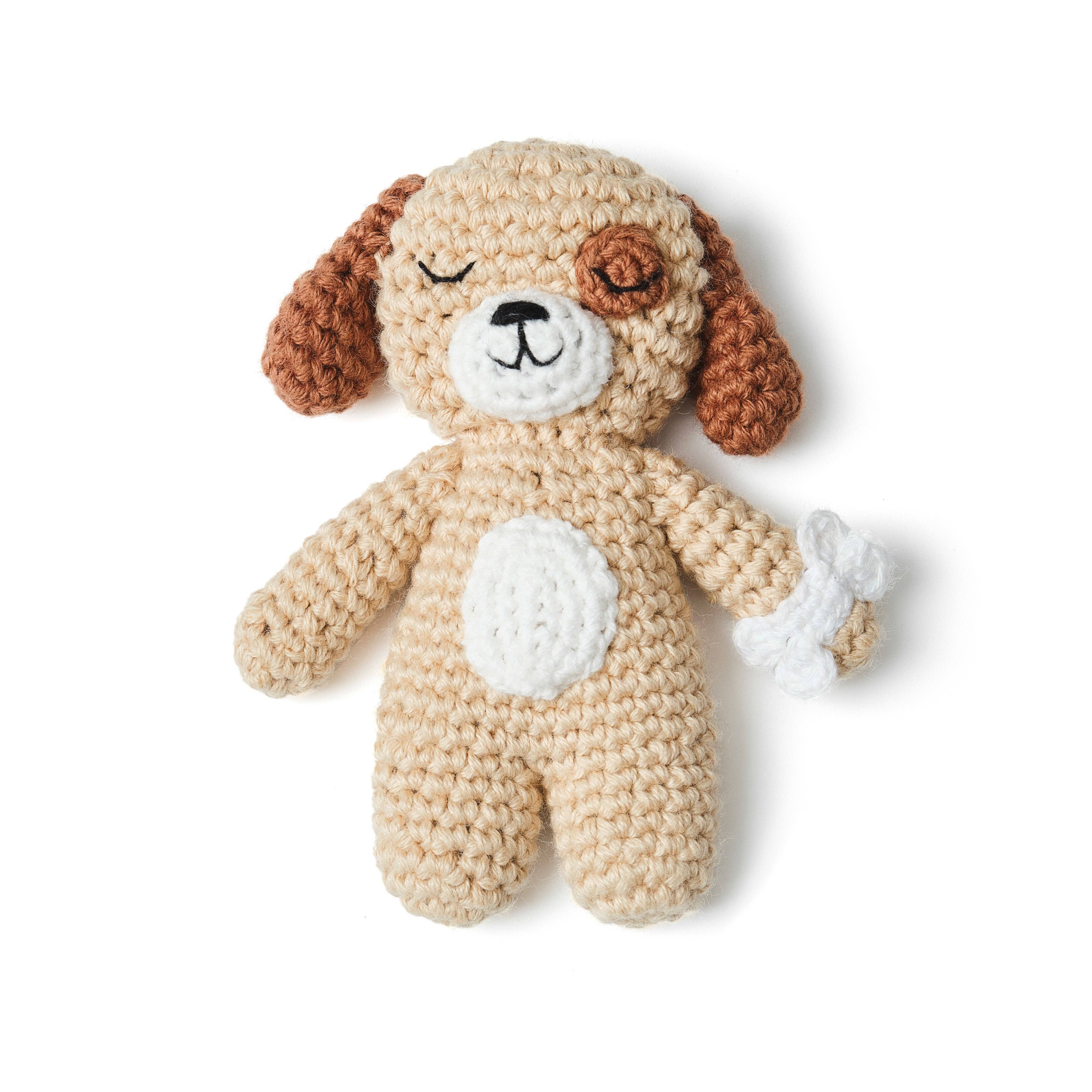 Crocheted dog toy with brown ears and white paws on a white background