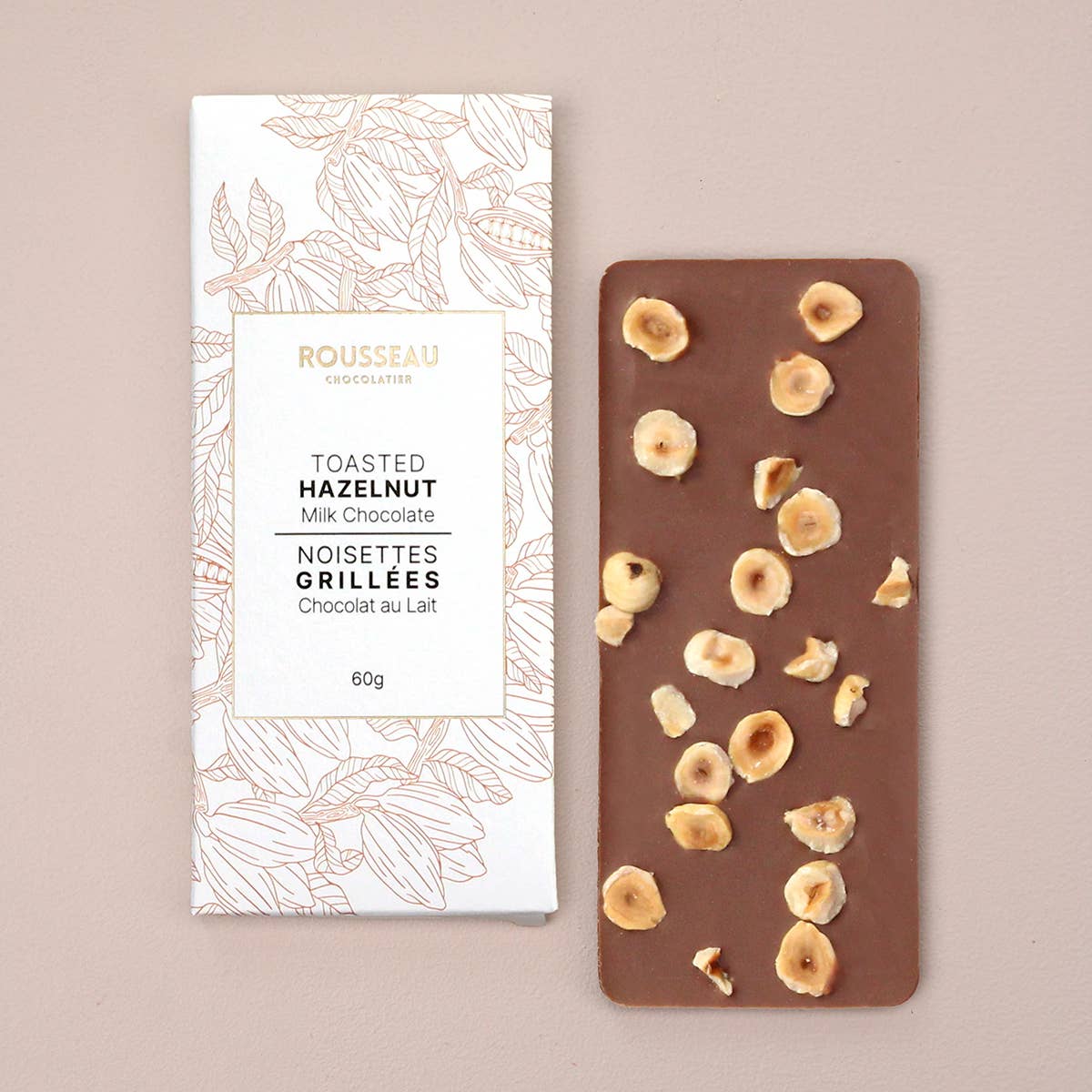 Chocolate bar with toasted hazelnuts and packaging on a beige background