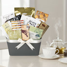 Gift basket with snacks and a teacup on a table