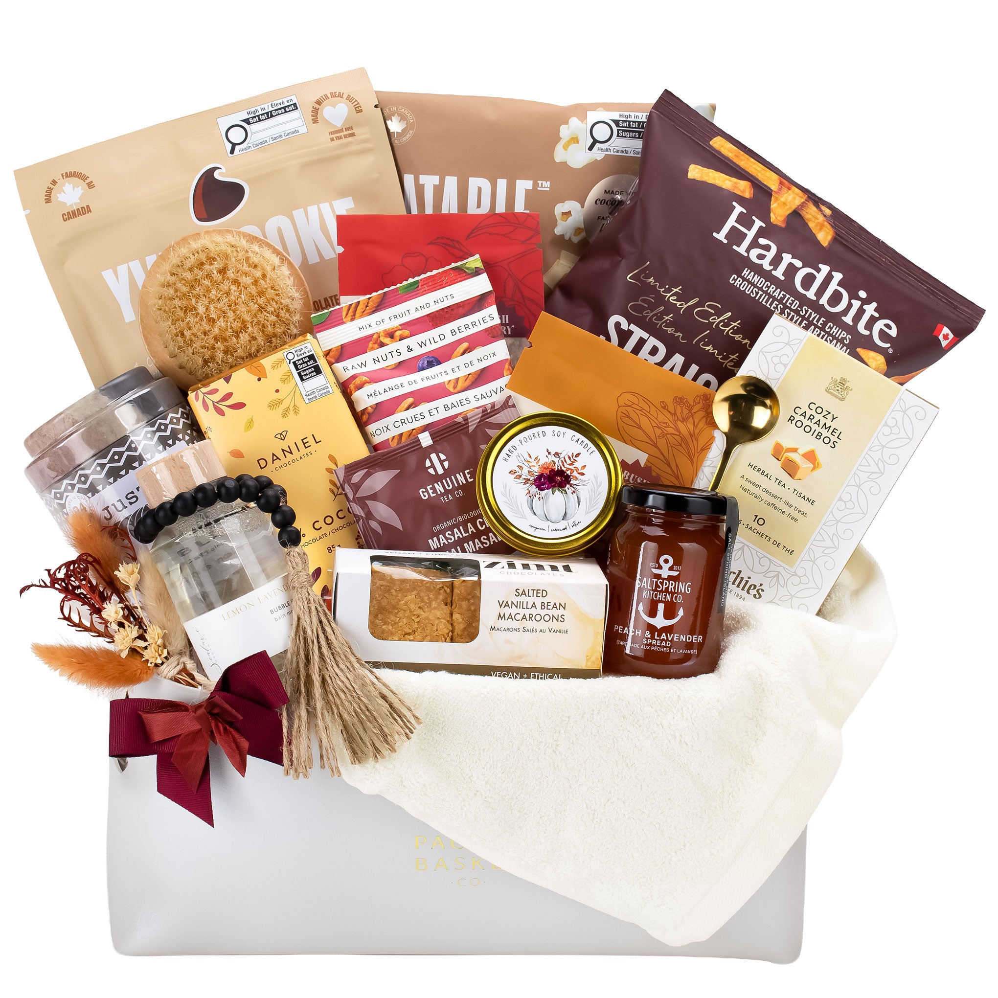 A curated gourmet gift basket from Pacific Basket Company, featuring an assortment of snacks, cookies, and treats arranged in a white basket. Visible brands include Hardbite, Daniel Chocolates, Murchies Tea, Zimt Chocolates, YVR Cookies, Eatable popcorn. 
