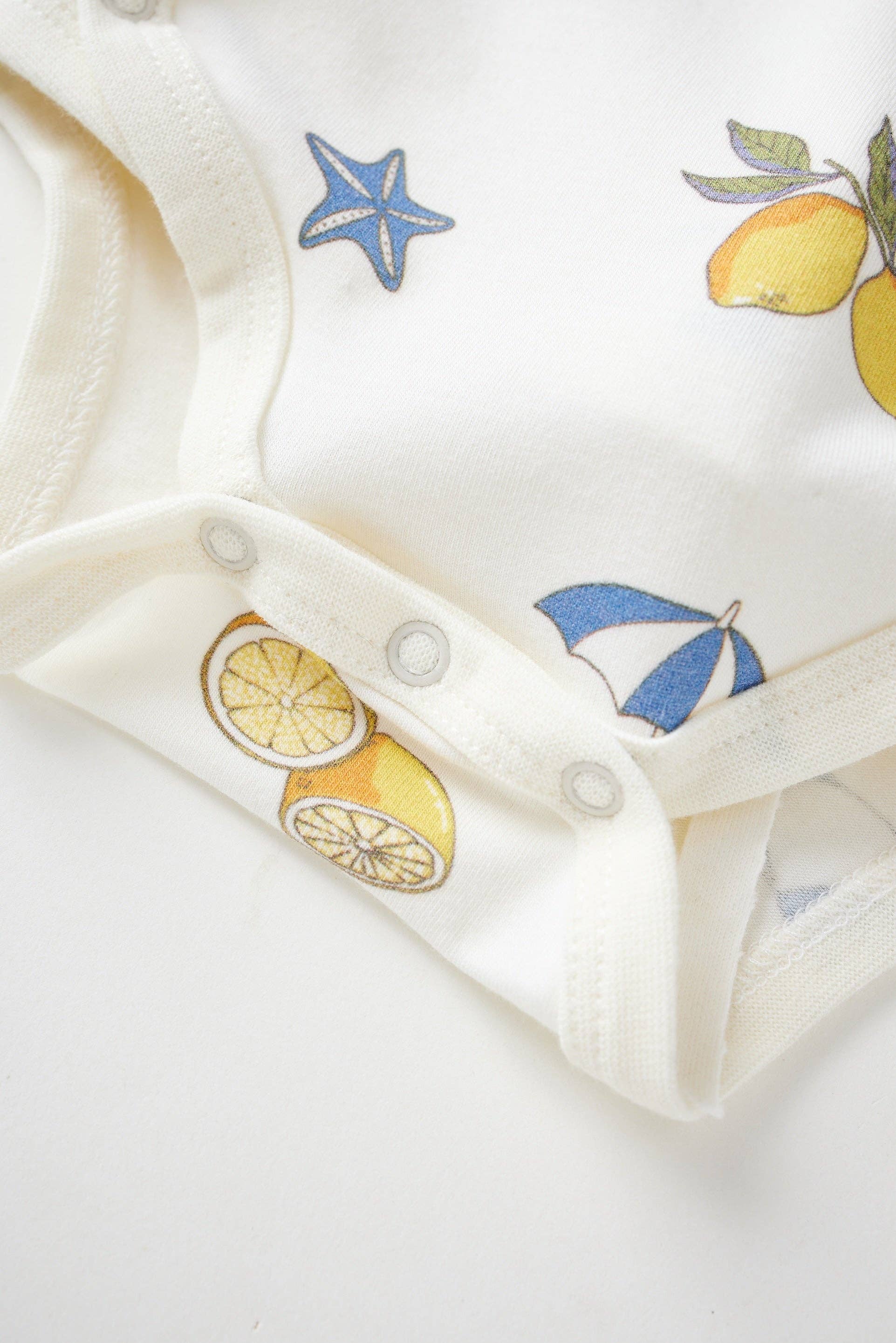 Close-up of a baby outfit with lemon and starfish patterns on a white background