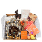 Easter gift box featuring chocolate popcorn, two chocolate bars, orange-toned artisan tea, and a Happy bath bomb in a mailer box.