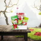 Gift box with snacks on a wooden table with decorative trees in the background