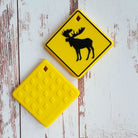 Two yellow moose crossing signs on a wooden surface