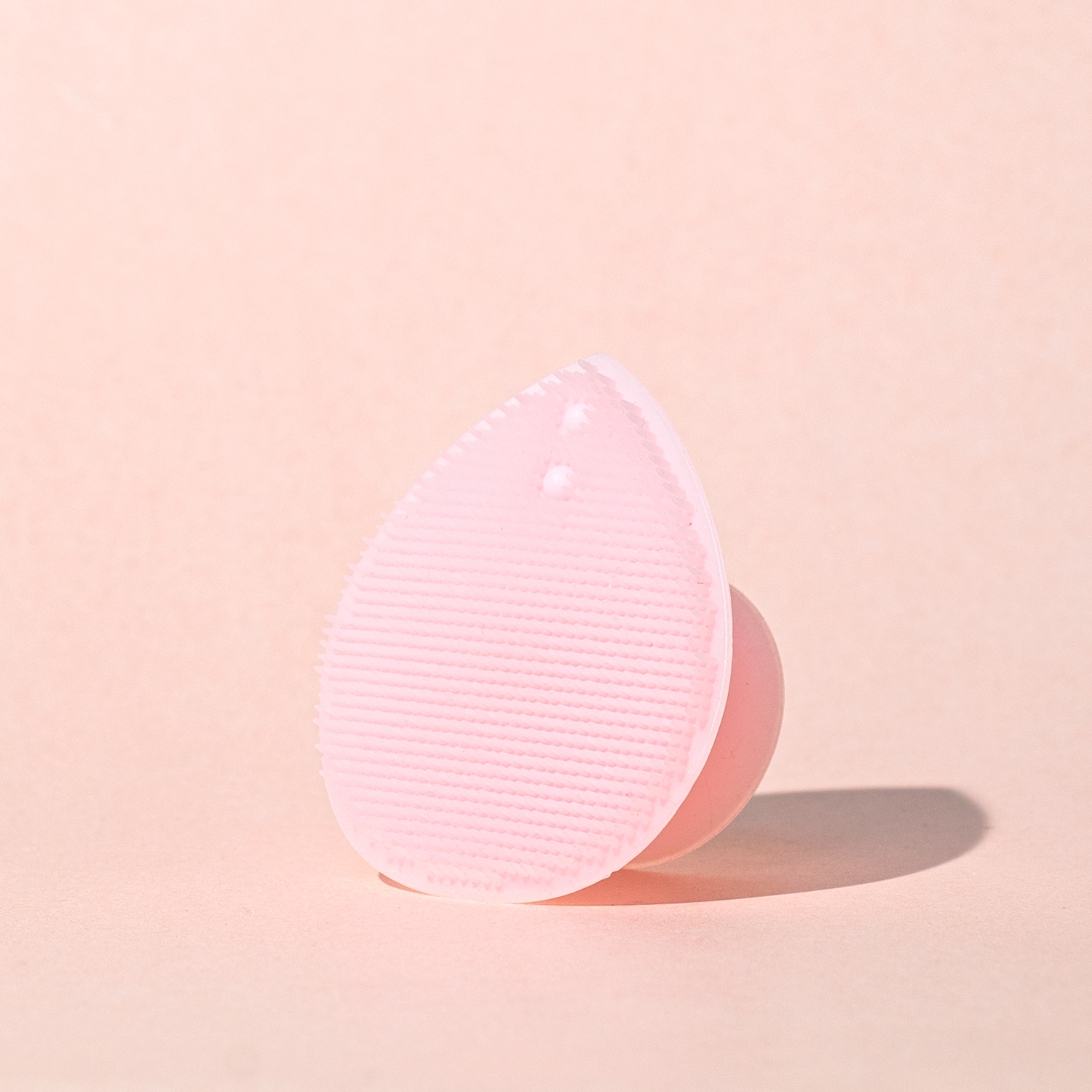 Pink silicone scrubber on a beige background