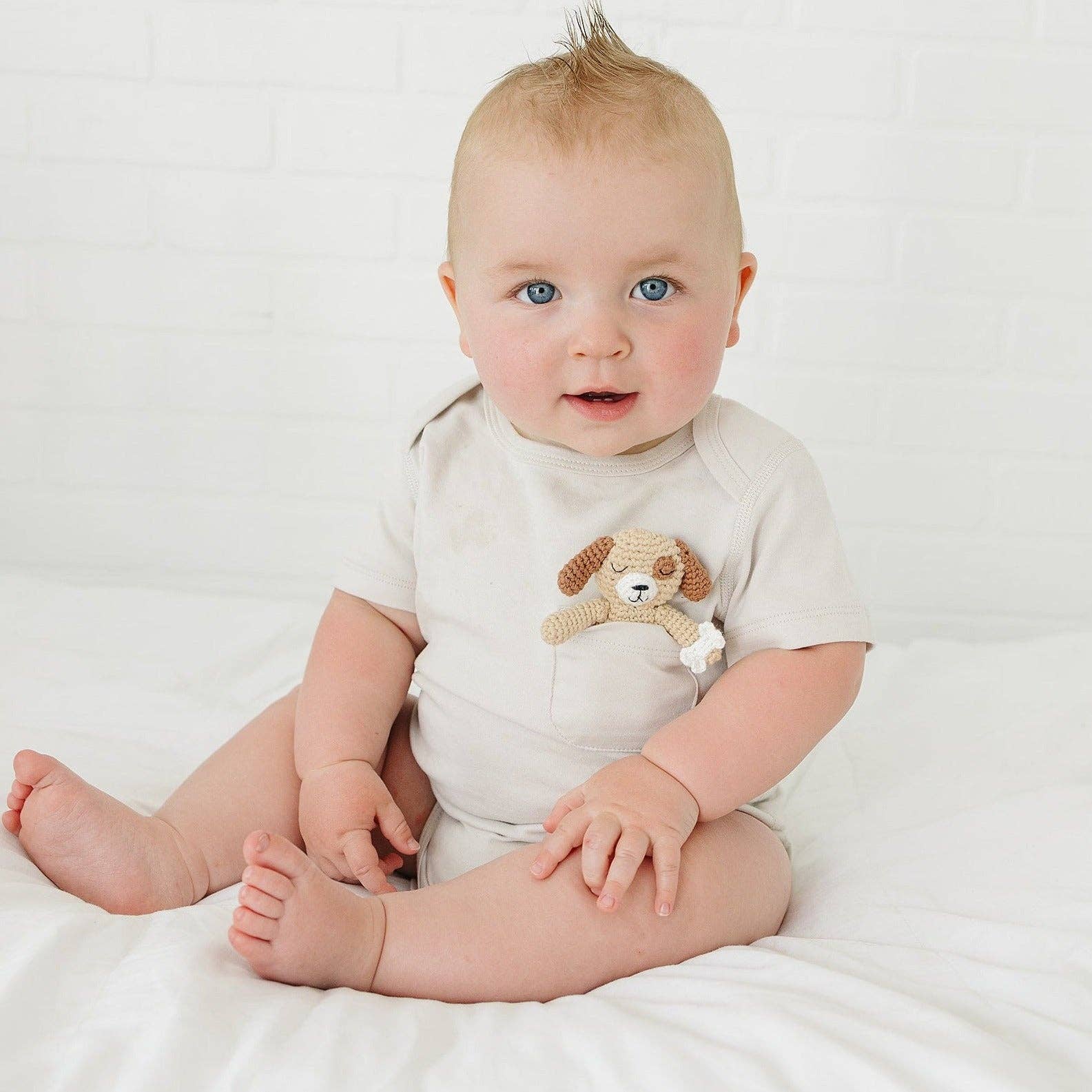 Baby wearing a white onesie with a dog design on a white background